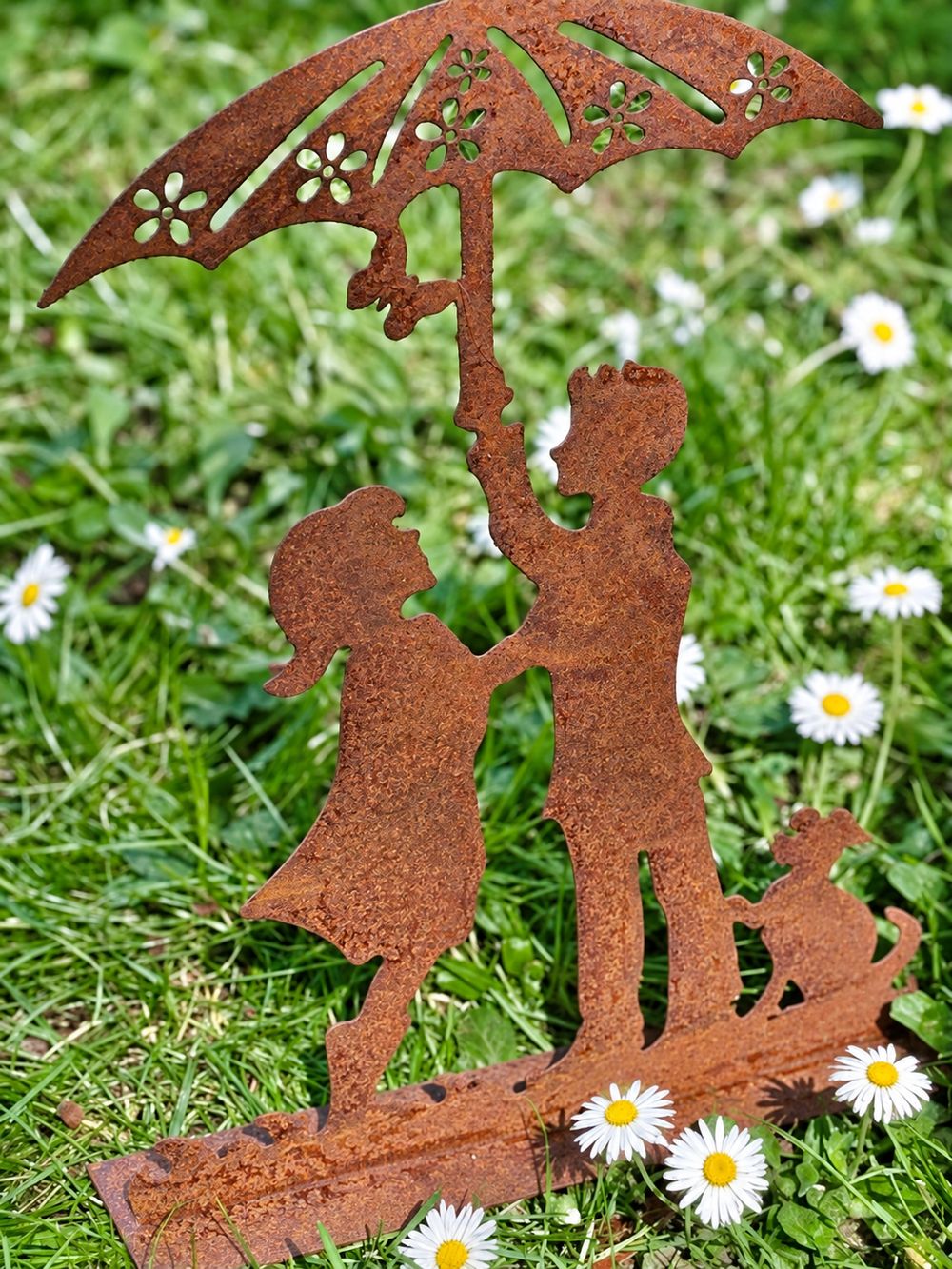 Détail de la patine rouillée des enfants, du chien et de l’ombrelle ajourée de la décoration Les Amoureux au Jardin.