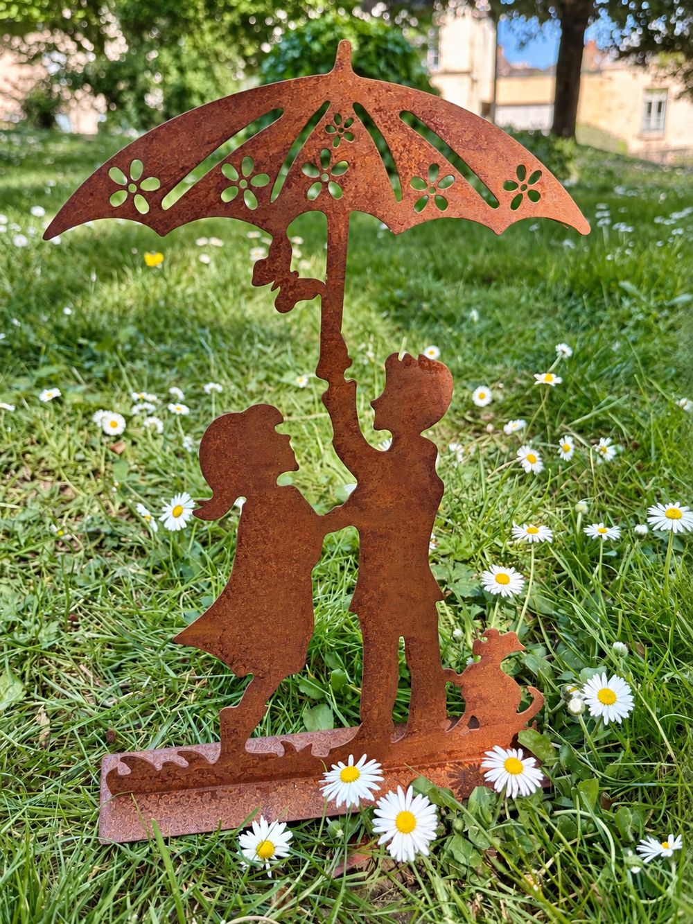 Décoration Les Amoureux au Jardin posée dans une pelouse fleurie de pâquerettes.