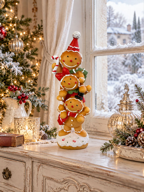 Figurine décorative de Noël composée de trois petits personnages façon pain d’épices superposés, aux tons caramel, rouge, vert et blanc, pour une décoration festive et féérique.