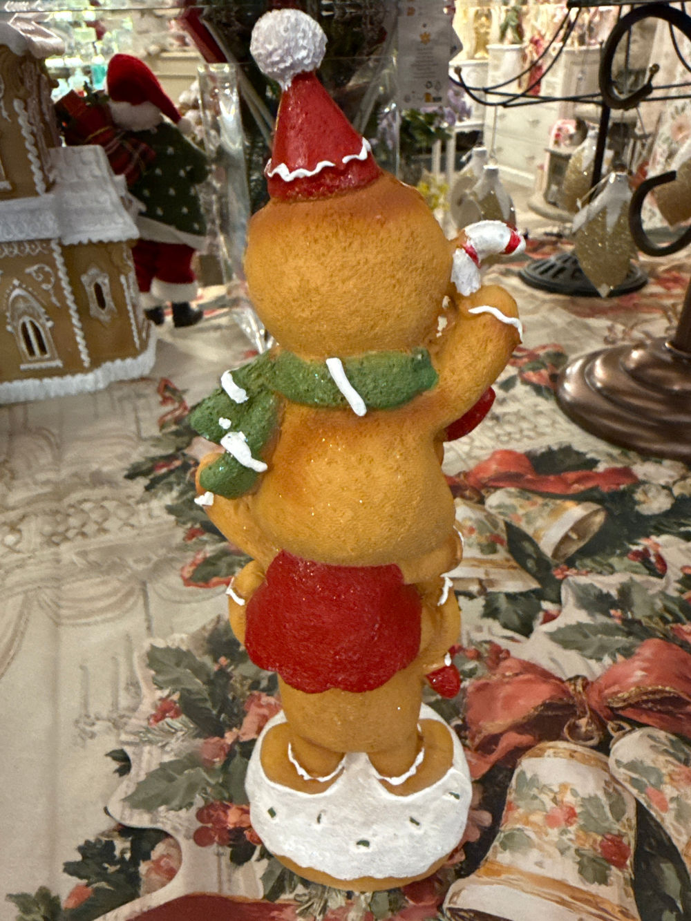 Figurine décorative de Noël composée de trois petits personnages façon pain d’épices superposés, aux tons caramel, rouge, vert et blanc, pour une décoration festive et féérique.