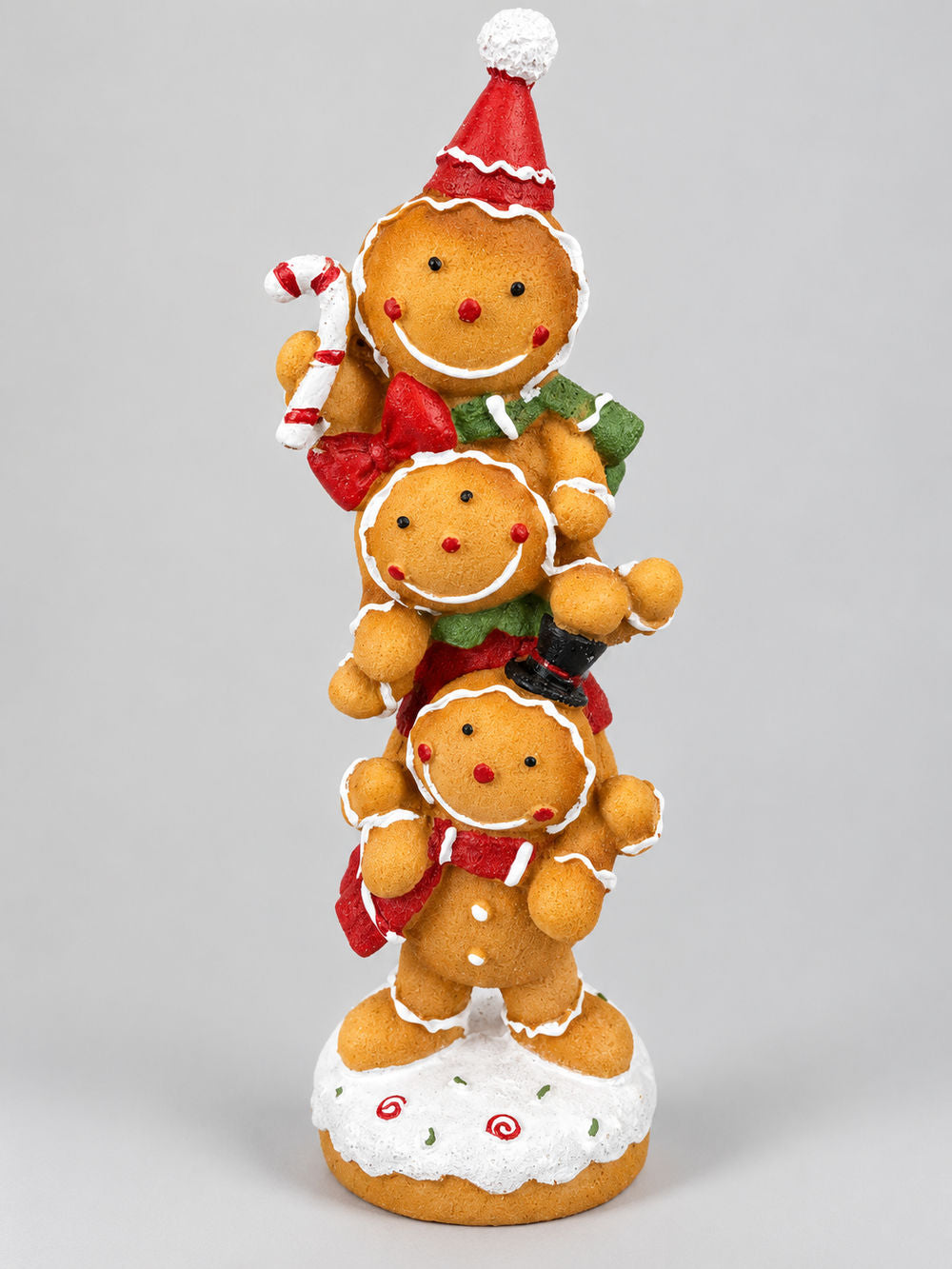Figurine décorative de Noël composée de trois petits personnages façon pain d’épices superposés, aux tons caramel, rouge, vert et blanc, pour une décoration festive et féérique.