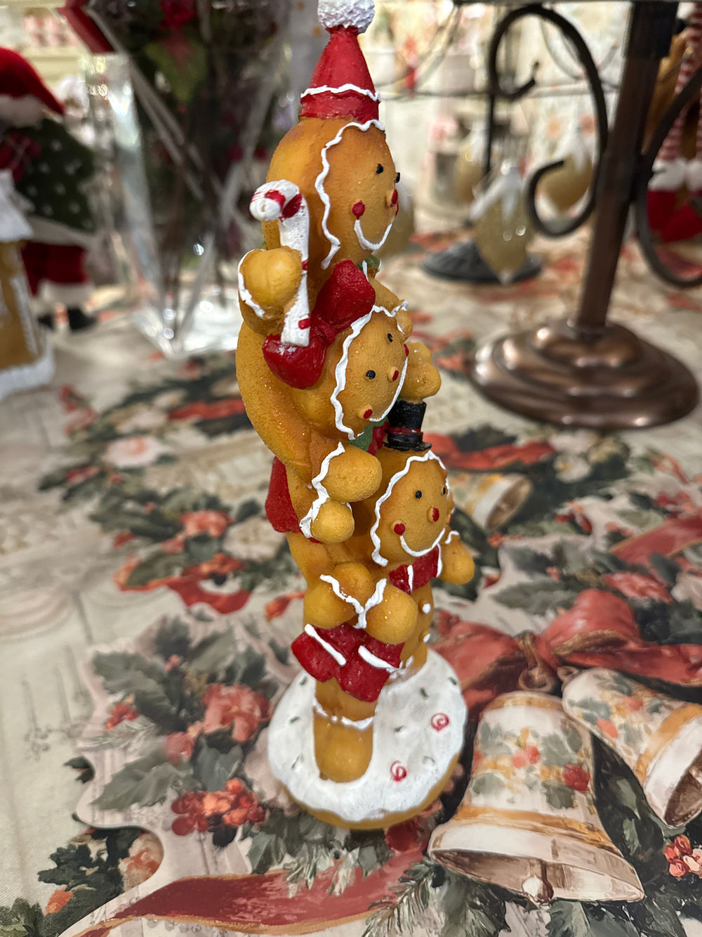 Figurine décorative de Noël composée de trois petits personnages façon pain d’épices superposés, aux tons caramel, rouge, vert et blanc, pour une décoration festive et féérique.