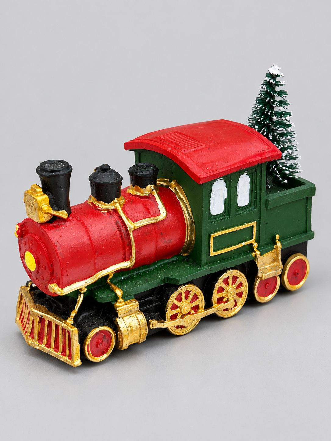Locomotive décorative de Noël rouge et verte, aux détails dorés et petit sapin enneigé, sur fond gris clair.