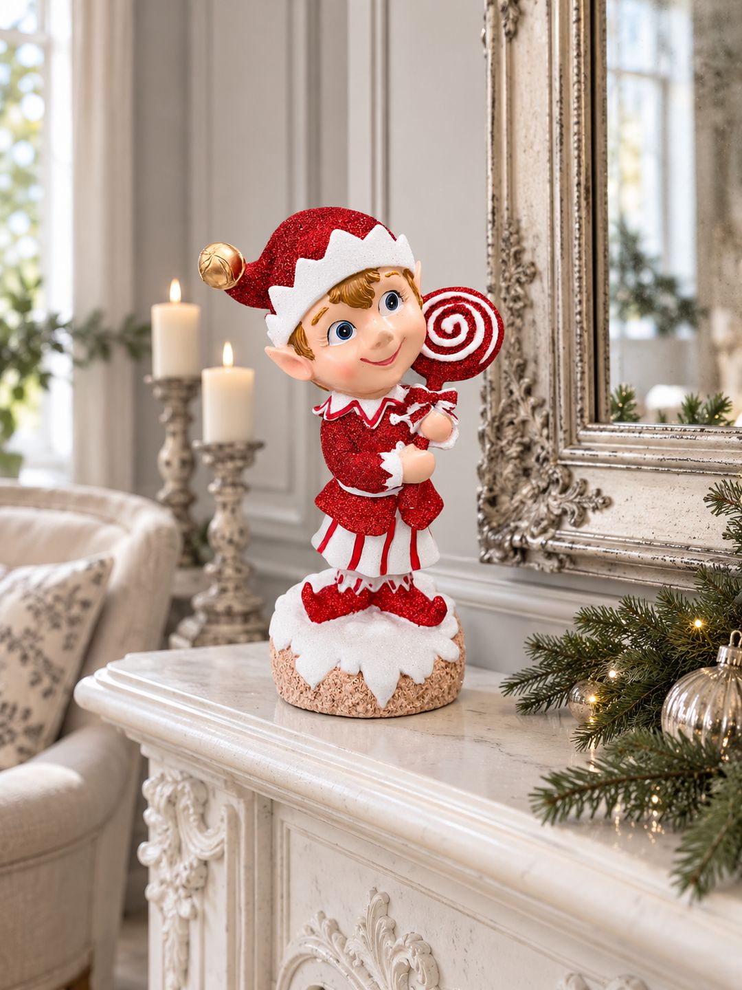 Lutin rouge pailleté sur une cheminée blanche dans un salon de charme, entouré d’un miroir ancien et de décorations de Noël discrètes.