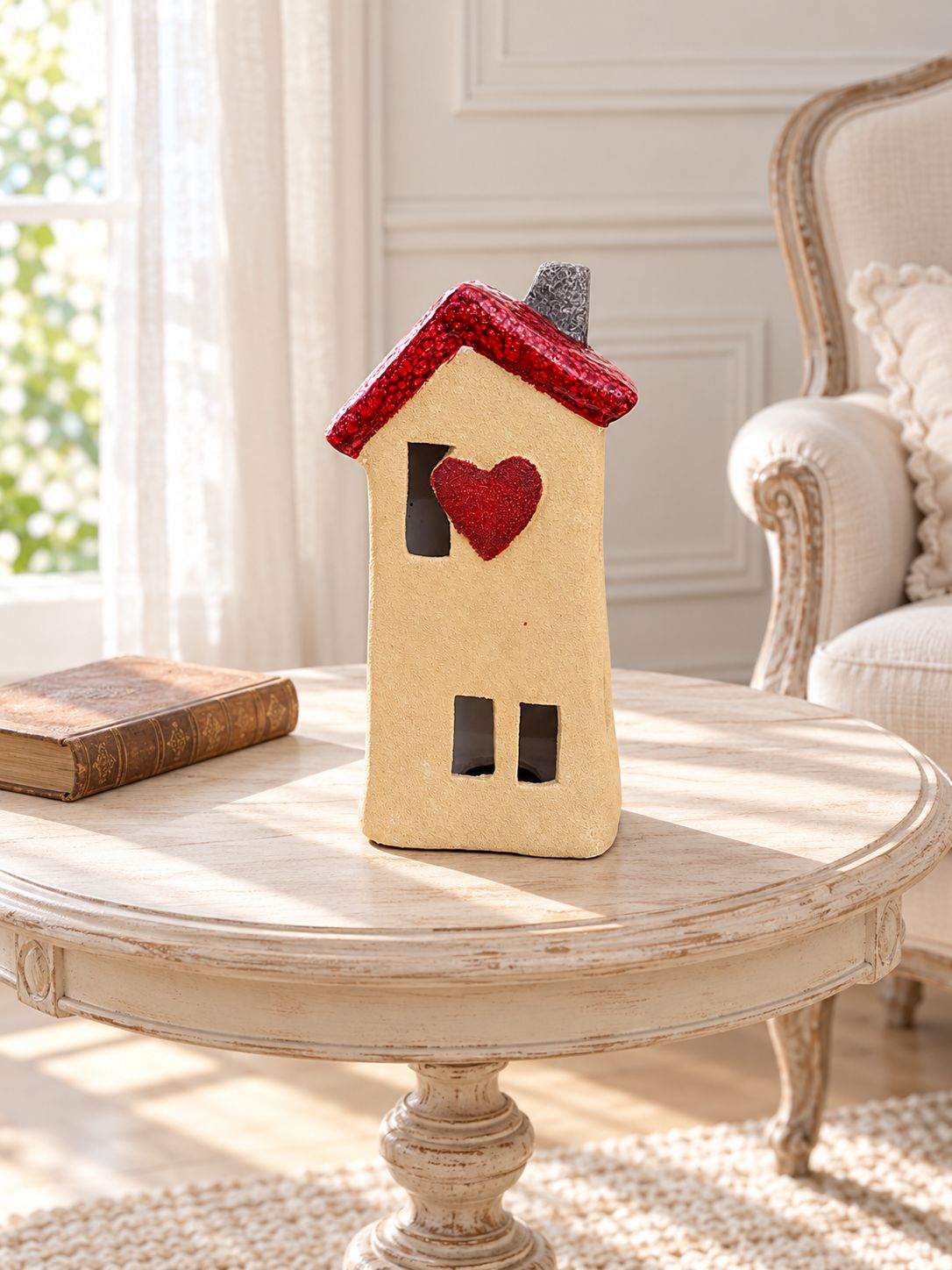 Maison photophore Cœur Rouge sur une table ronde patinée dans un salon lumineux au décor romantique.
