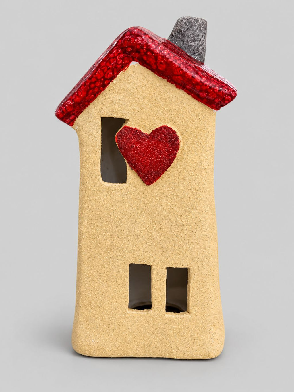 Maison photophore en terre cuite beige, avec toit rouge scintillant et cœur rouge en relief, sur fond gris clair.