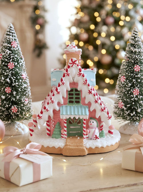Maisonnette pain d’épice décorative de Noël rose pastel, blanche et bleu ciel, avec décor enneigé et bonhomme de neige, pour ambiance de Noël féérique