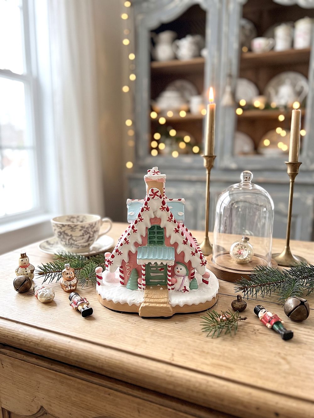 Maisonnette pain d’épice décorative de Noël rose pastel, blanche et bleu ciel, avec décor enneigé et bonhomme de neige, pour ambiance de Noël féérique