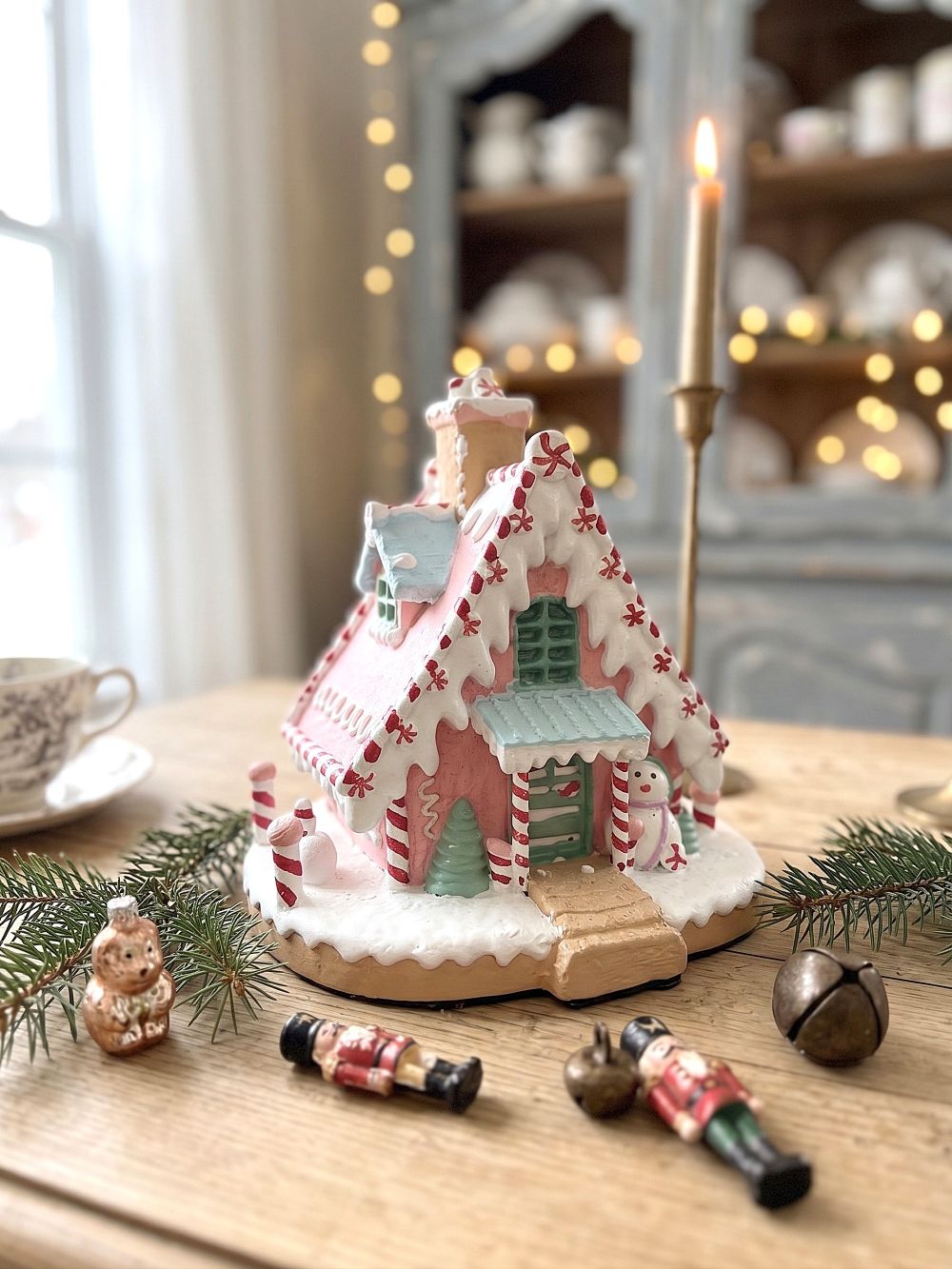 Maisonnette pain d’épice décorative de Noël rose pastel, blanche et bleu ciel, avec décor enneigé et bonhomme de neige, pour ambiance de Noël féérique