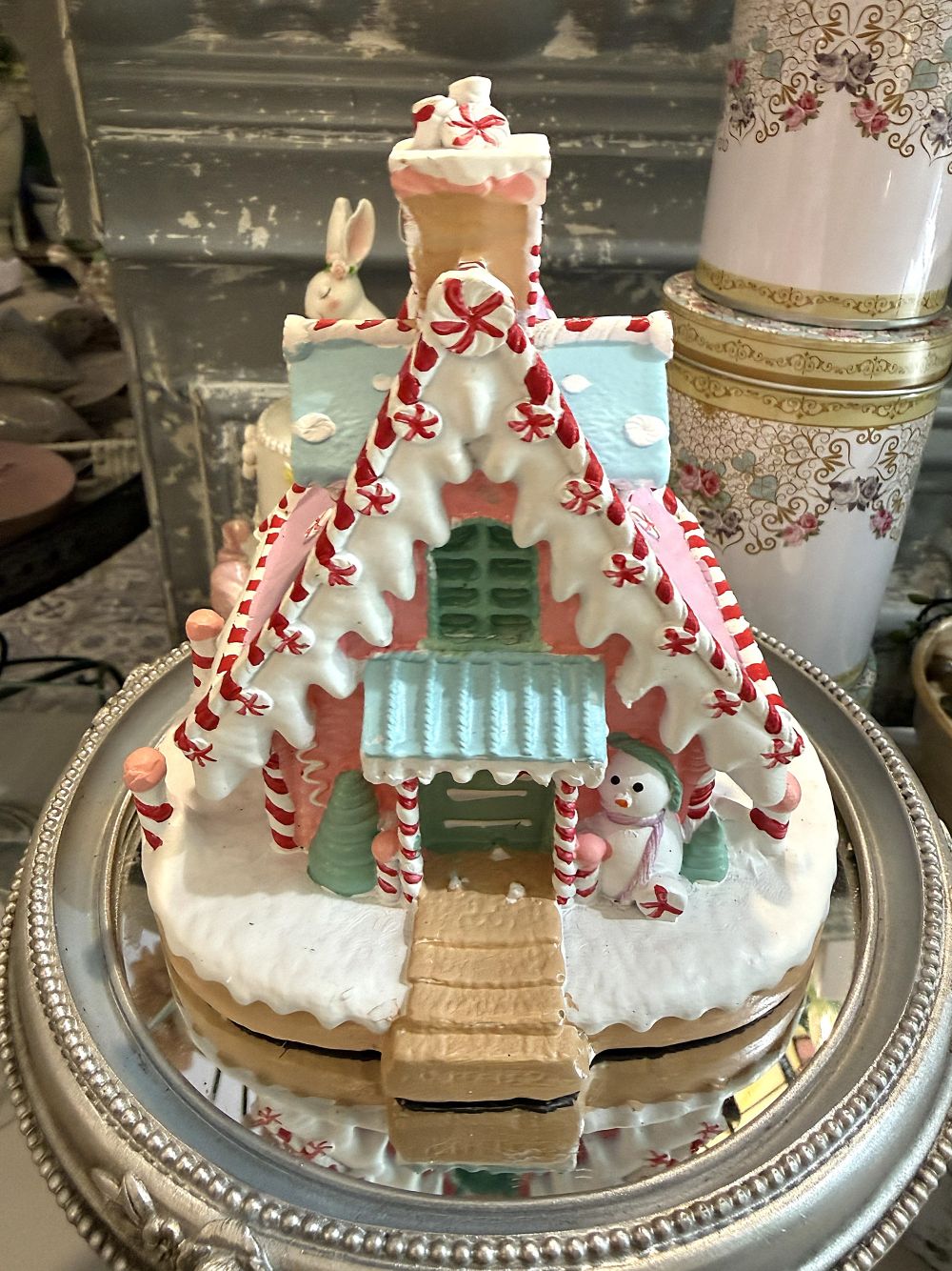 Maisonnette pain d’épice décorative de Noël rose pastel, blanche et bleu ciel, avec décor enneigé et bonhomme de neige, pour ambiance de Noël féérique