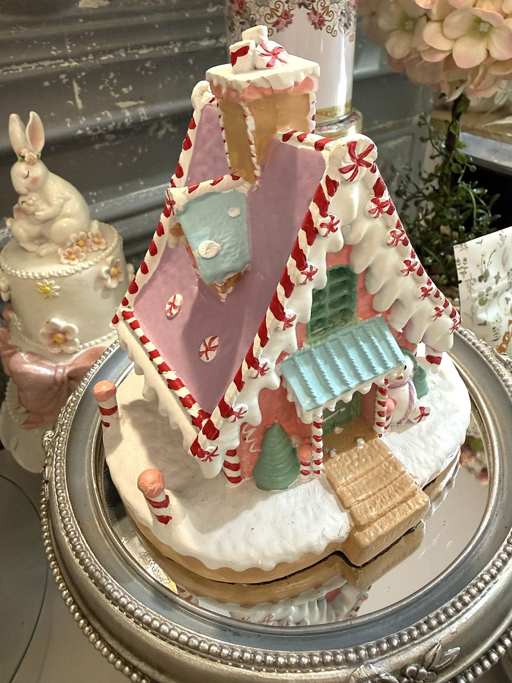 Maisonnette pain d’épice décorative de Noël rose pastel, blanche et bleu ciel, avec décor enneigé et bonhomme de neige, pour ambiance de Noël féérique