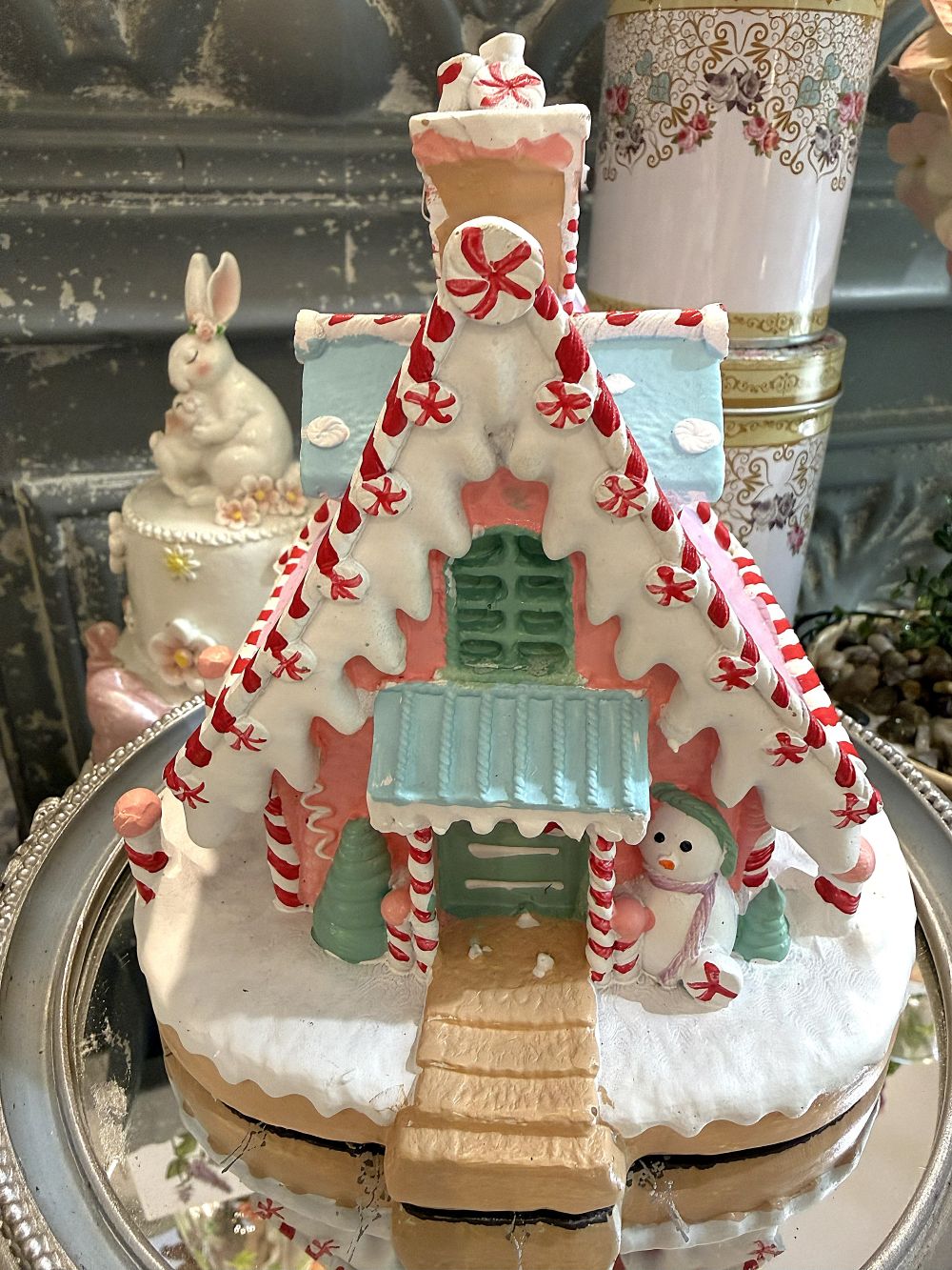 Maisonnette pain d’épice décorative de Noël rose pastel, blanche et bleu ciel, avec décor enneigé et bonhomme de neige, pour ambiance de Noël féérique