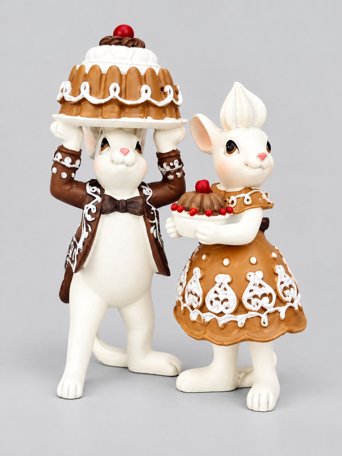 Duo de figurines en résine Mr et Mme Pâtissouries, portant des gâteaux, présenté sur fond gris clair.