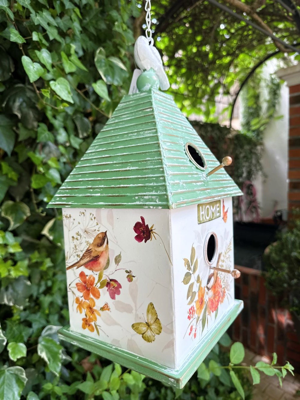 Nichoir décoratif suspendu en métal peint avec motifs de fleurs, oiseaux et papillons, toit vert et finition shabby chic, hauteur totale 73 cm