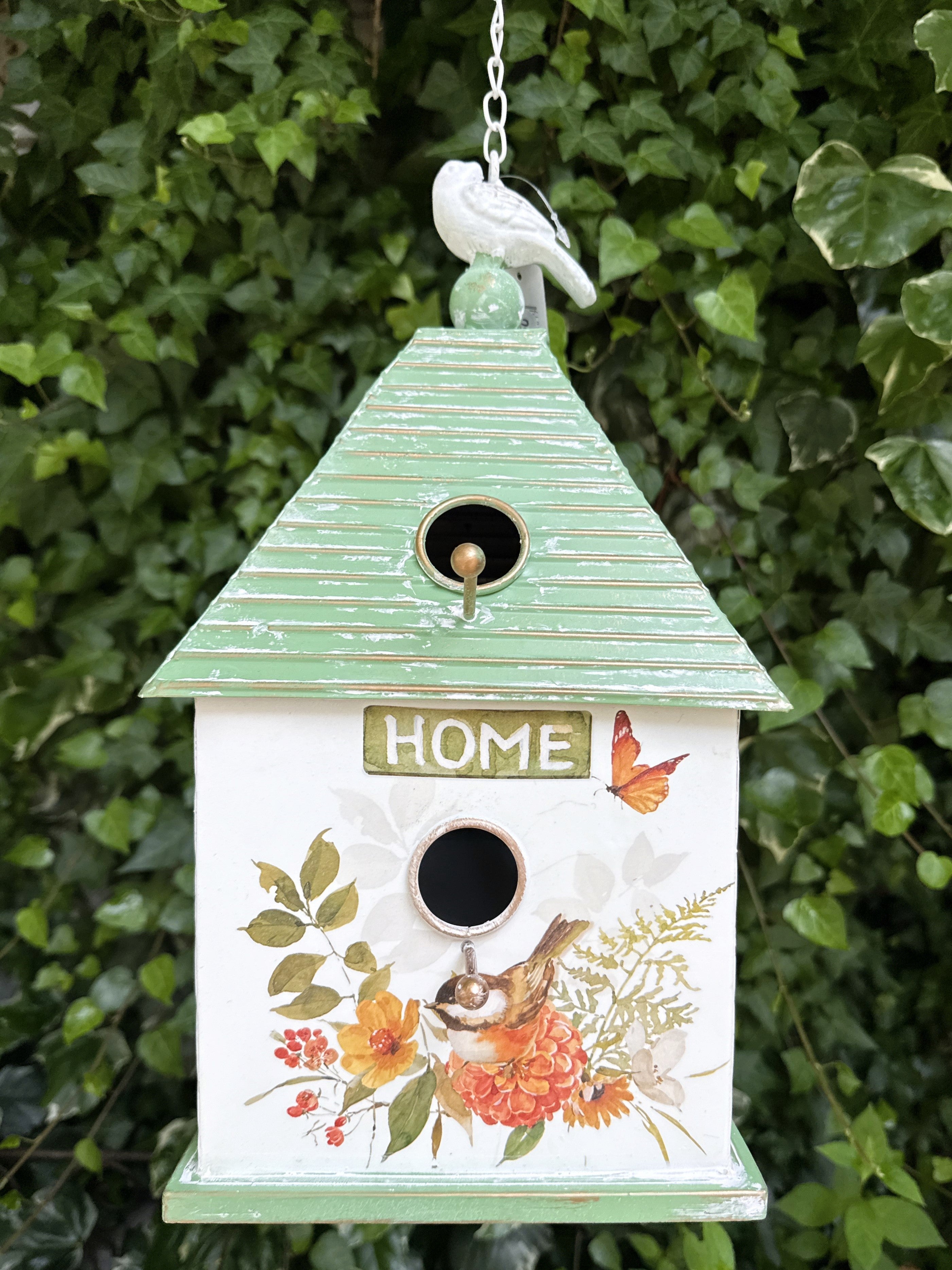 Nichoir décoratif suspendu en métal peint avec motifs de fleurs, oiseaux et papillons, toit vert et finition shabby chic, hauteur totale 73 cm