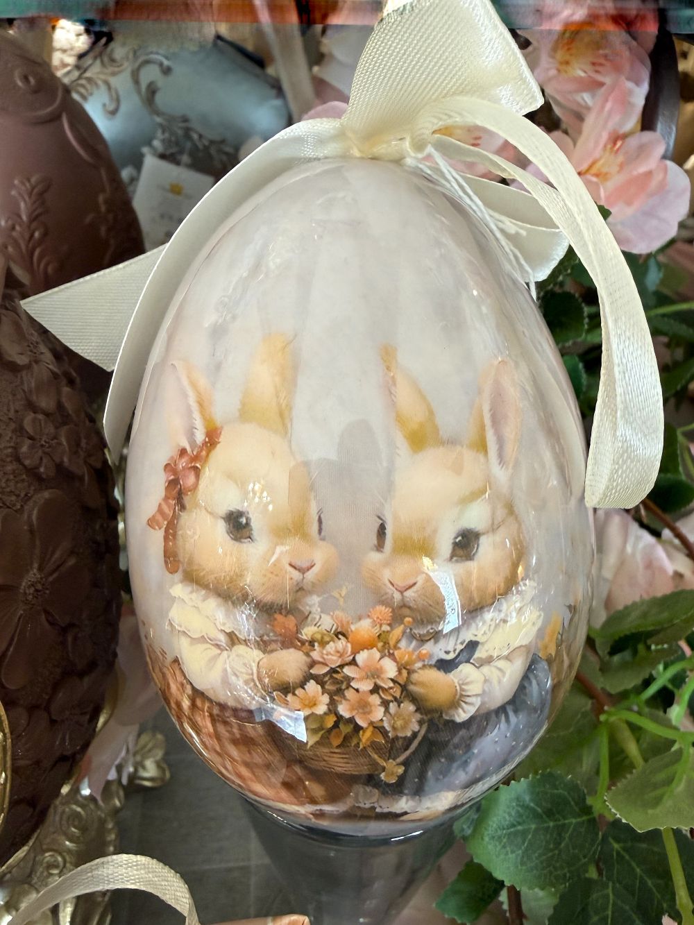 Œuf décoratif romantique Blanc Mariclò avec illustration de lapins tenant des fleurs, tons blanc beige et rose poudré, ambiance shabby chic et décoration de charme printanière