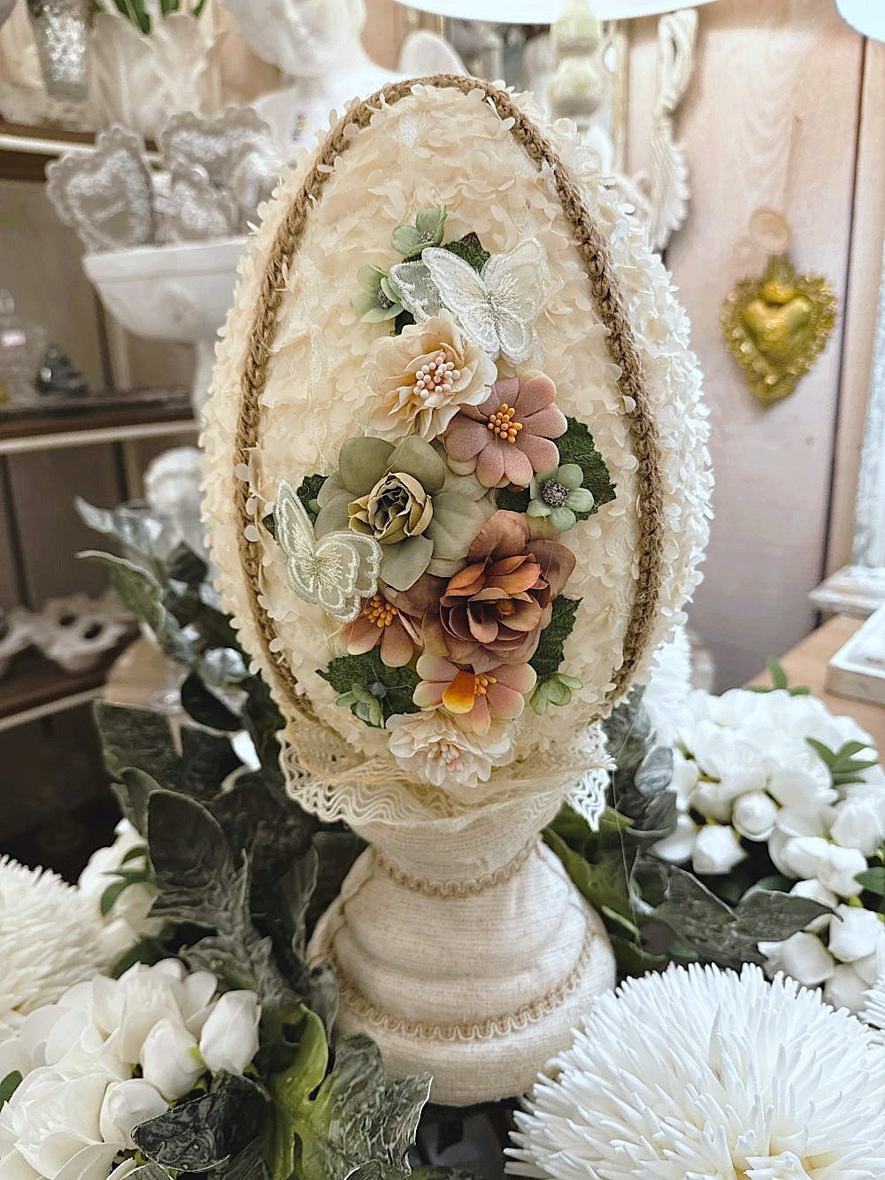 Œuf décoratif en style shabby chic orné de fleurs en tissu et de papillons, dans les tons ivoire, vieux rose et vert sauge, pour une ambiance romantique et poétique.