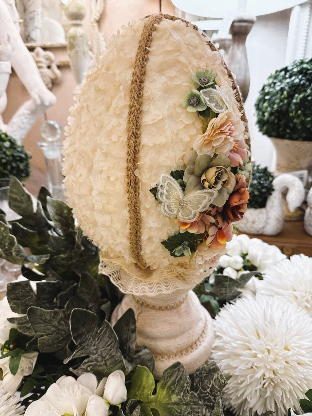 Œuf décoratif en style shabby chic orné de fleurs en tissu et de papillons, dans les tons ivoire, vieux rose et vert sauge, pour une ambiance romantique et poétique.