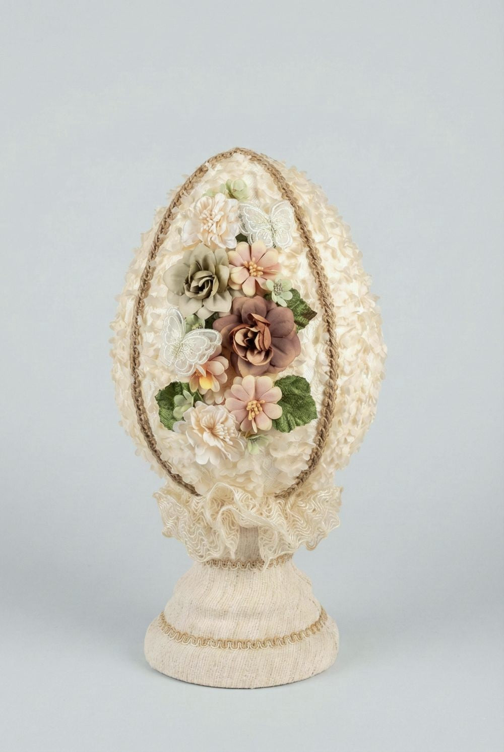 Œuf décoratif en style shabby chic orné de fleurs en tissu et de papillons, dans les tons ivoire, vieux rose et vert sauge, pour une ambiance romantique et poétique.