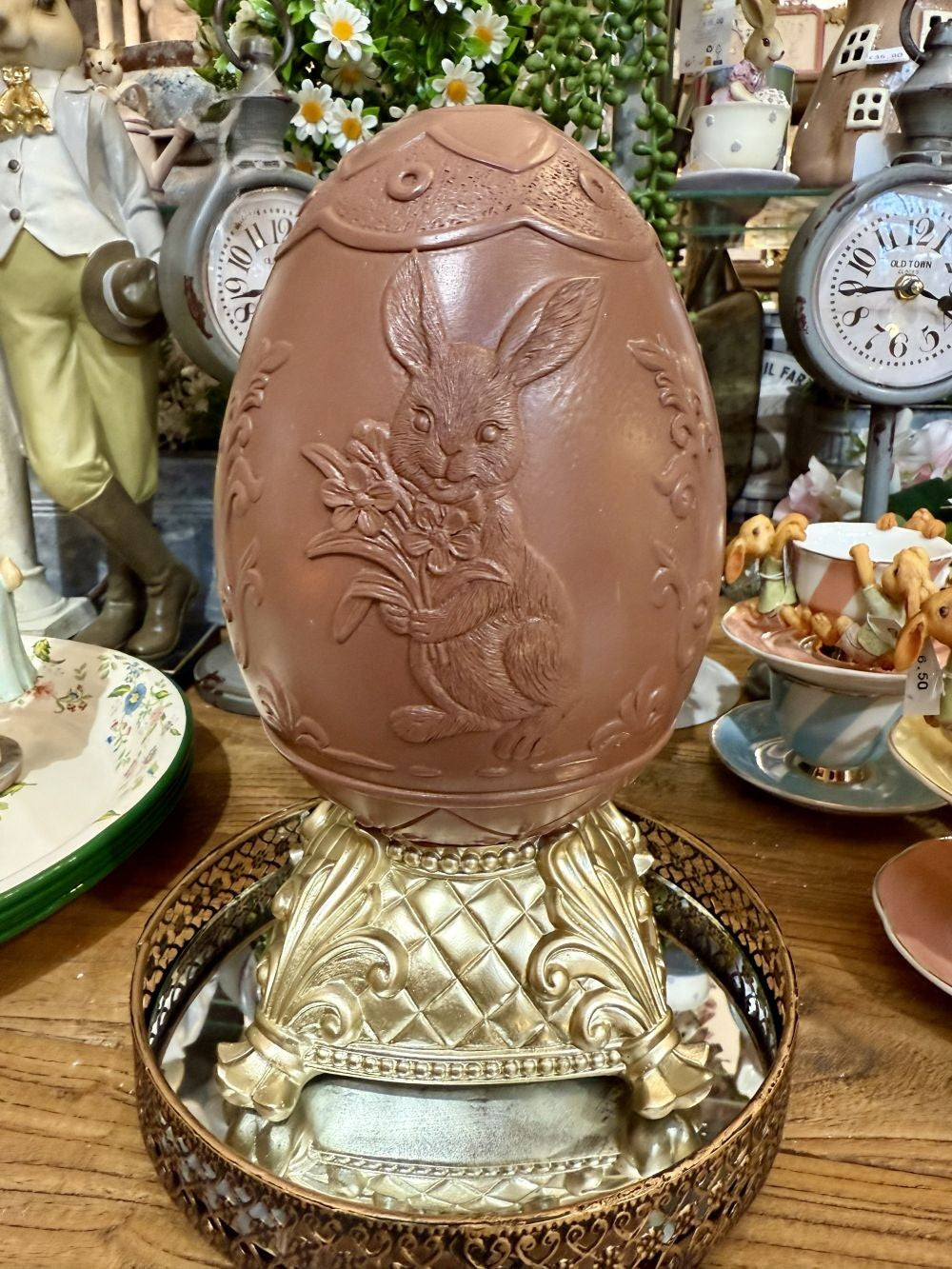 Œuf de Pâques décoratif sur piédestal doré, coloris brun et beige, avec relief de lapin fleuri, idéal pour une décoration de charme romantique et printanière sur une table, un buffet ou une console