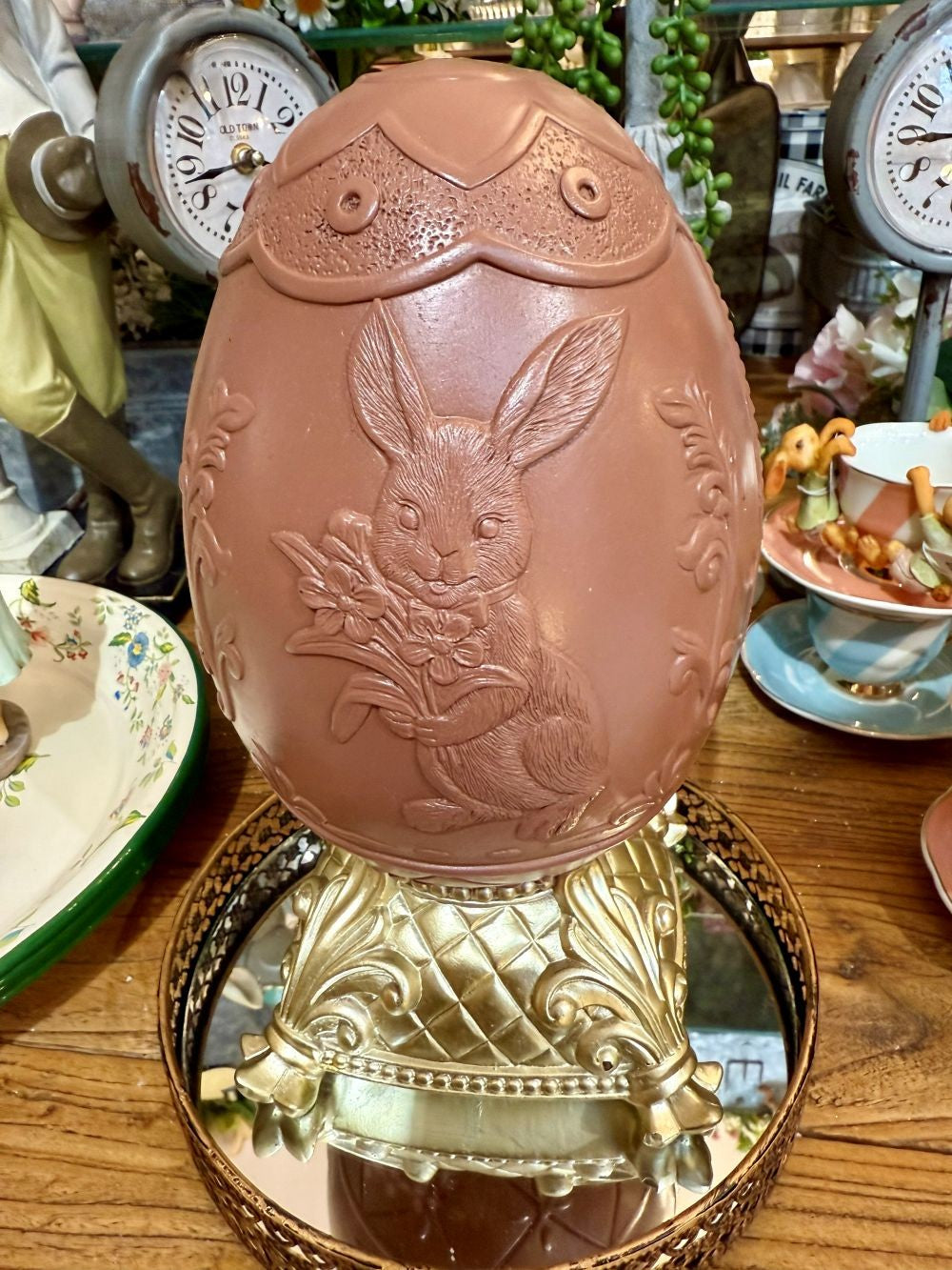 Œuf de Pâques décoratif sur piédestal doré, coloris brun et beige, avec relief de lapin fleuri, idéal pour une décoration de charme romantique et printanière sur une table, un buffet ou une console