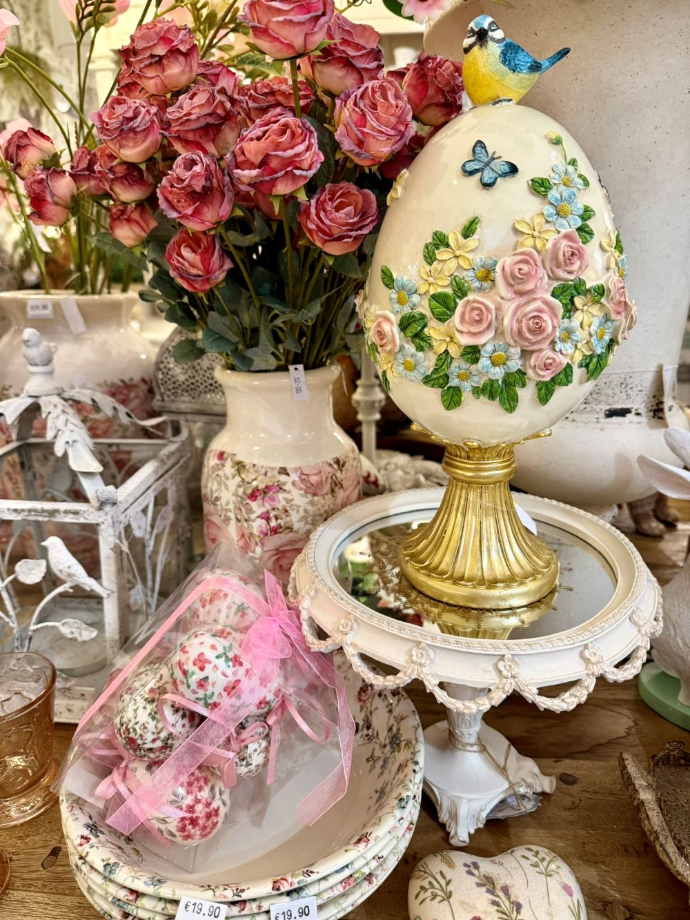 Œuf décoratif romantique blanc crème avec fleurs roses et bleues en relief, oiseau bleu sur le dessus et pied doré, décoration shabby chic et poétique.