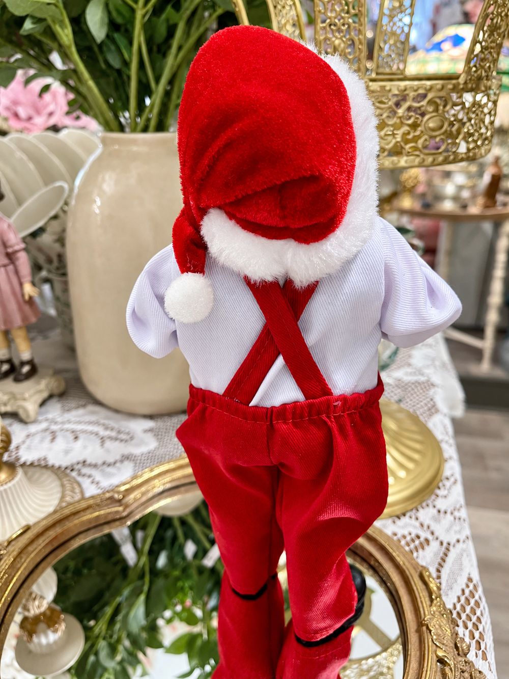 Vue de dos du Père Noël Esprit des Vignes, avec ses bretelles rouges croisées et son bonnet à pompon blanc.
