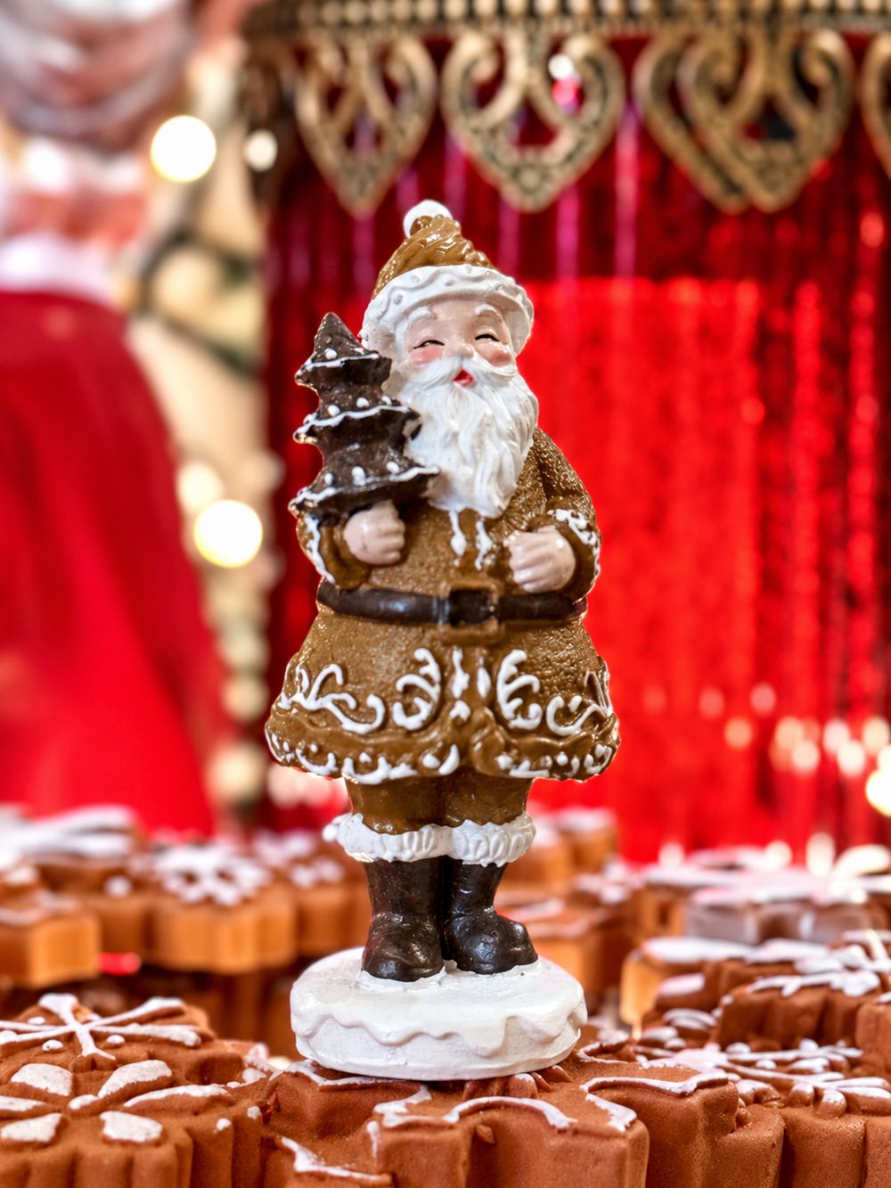 Père Noël Pain d’Épices Miniature sur son socle blanc dans un décor de biscuits de Noël.
