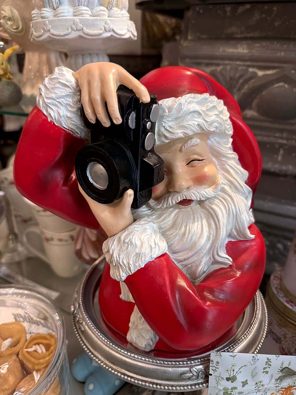 Vue de face de la figurine Père Noël rouge et blanc tenant un appareil photo noir