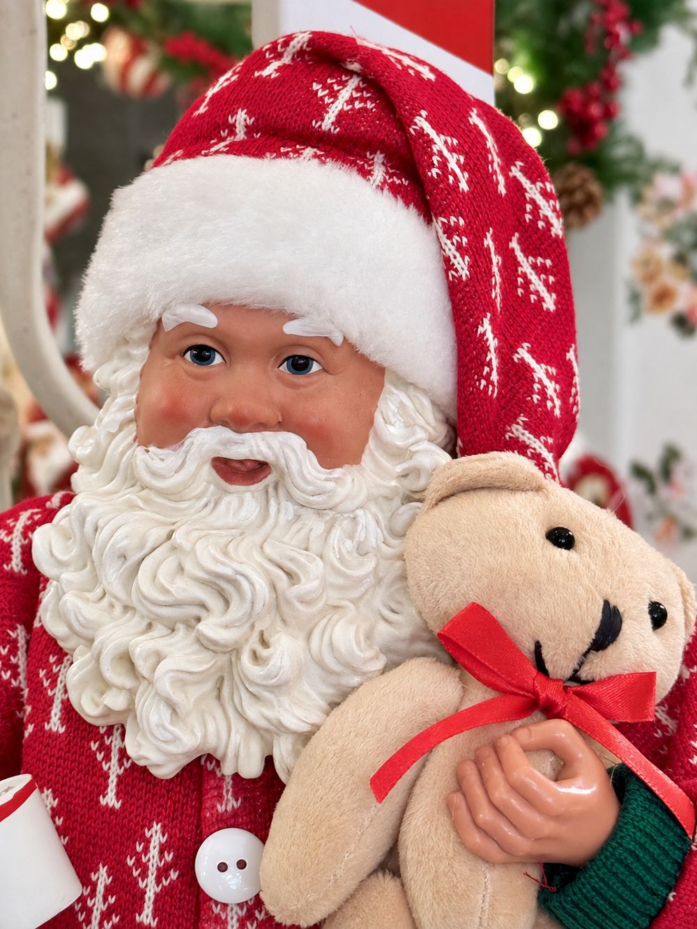 Gros plan du visage du Père Noël, de son bonnet rouge et de l’ourson crème au ruban rouge.