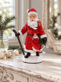 Figurine Père Noël Randonnée sur une console blanche patinée, près d’un miroir ancien et de boules de Noël.