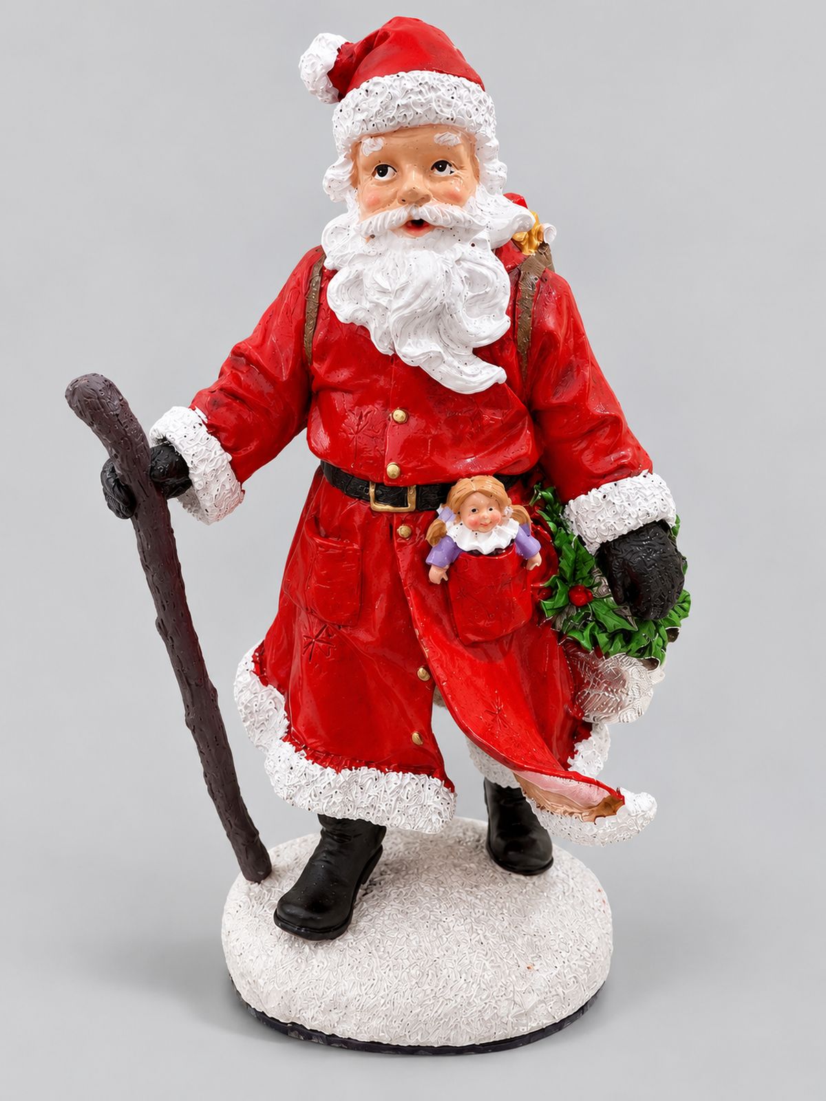 Figurine Père Noël Randonnée de 22 cm, en manteau rouge avec bâton et hotte de cadeaux, sur fond gris clair.