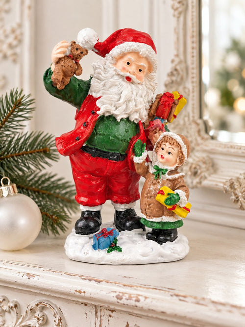 Figurine Père Noël et enfant sur une console patinée, devant un miroir ancien, avec une branche de sapin et une boule blanche.