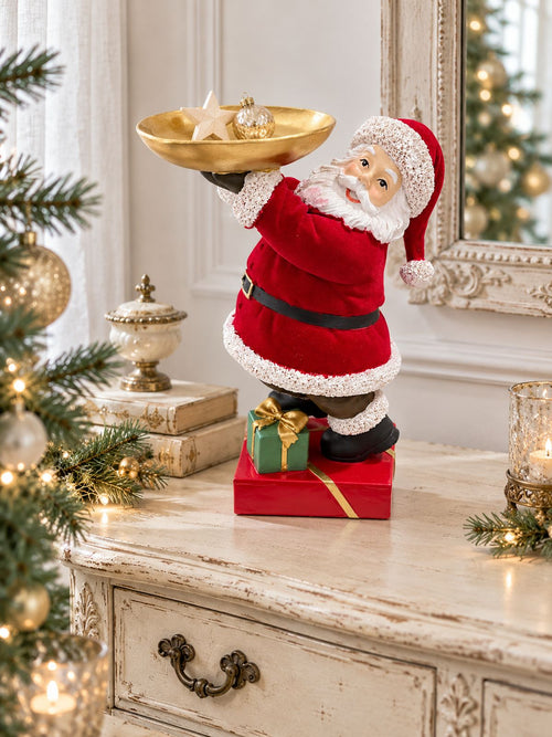 Père Noël serviteur sur une commode ancienne, avec une étoile et une boule de Noël dans son plateau doré.