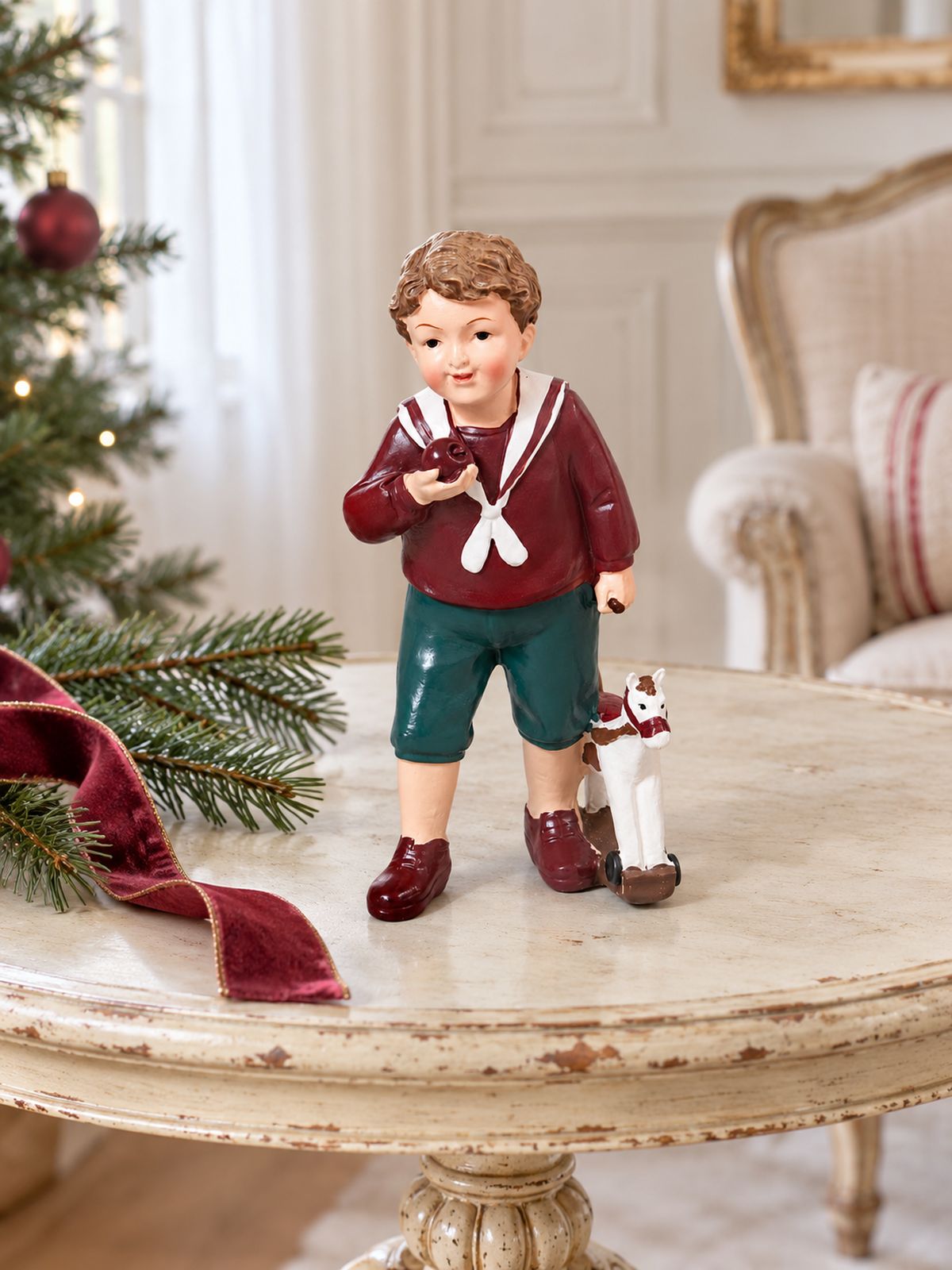 Figurine Petit Garçon au Cheval sur un guéridon patiné dans un salon lumineux décoré pour Noël.