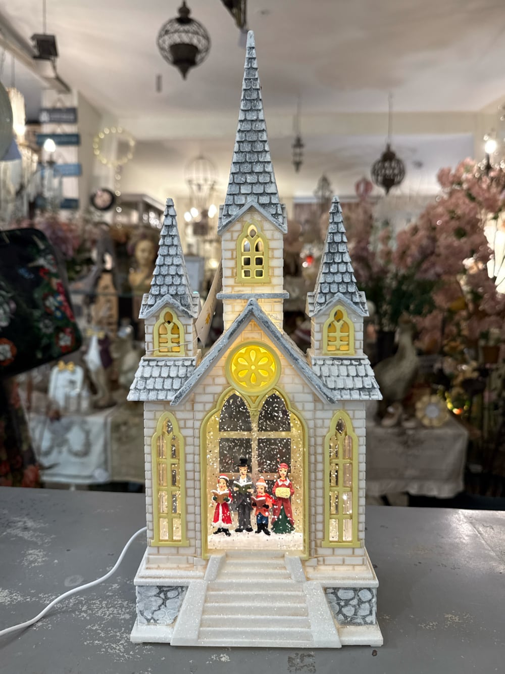 Chapelle de Noël lumineuse avec chorale miniature, éclairage chaleureux et paillettes animées, décoration féérique de village de Noël romantique