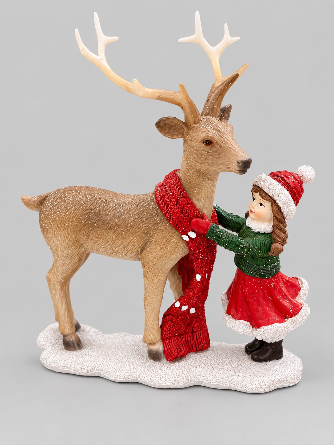 Figurine Petite Fille et Son Cerf sur fond gris clair, fillette en rouge et vert auprès d’un cerf à écharpe rouge.