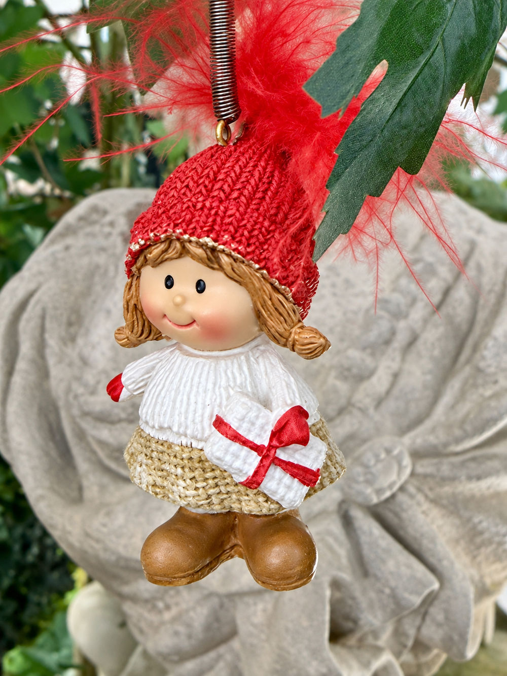 Petite fille de Noël sur ressort vue de face avec bonnet rouge et petit cadeau