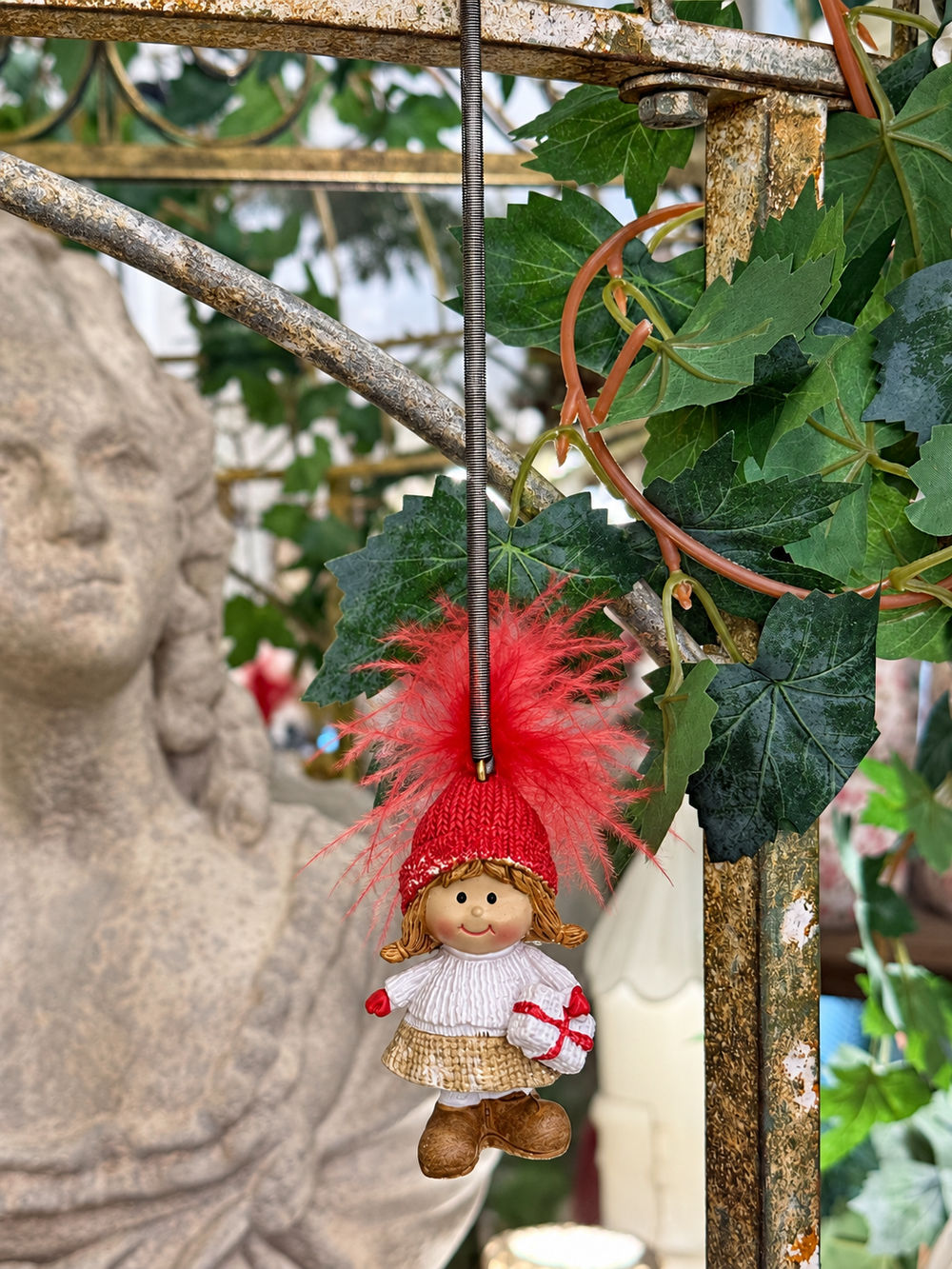Petite fille de Noël suspendue par son ressort avec bonnet rouge et petit cadeau