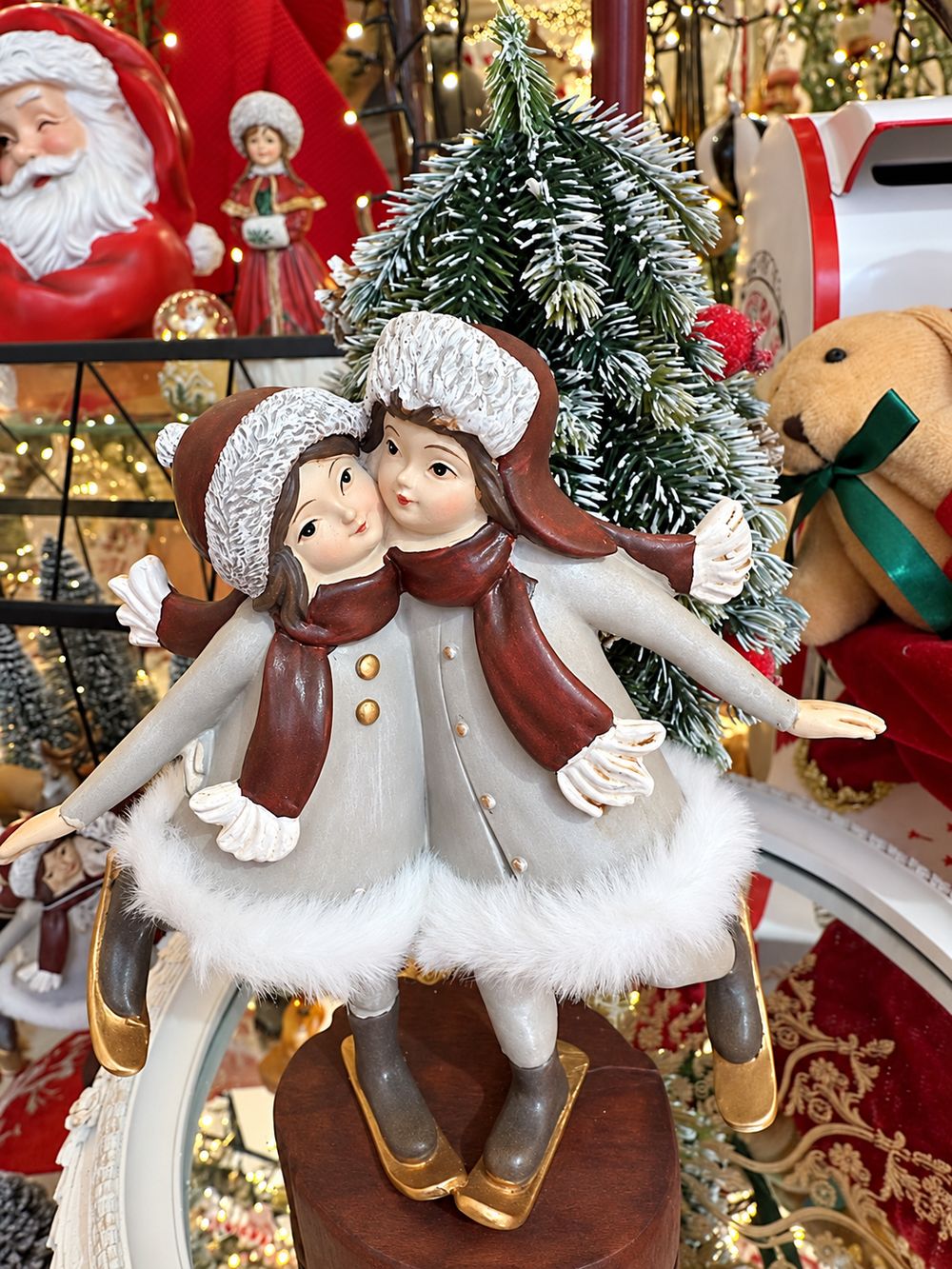 Vue rapprochée de la figurine Les Petites Skieuses devant un sapin de Noël.