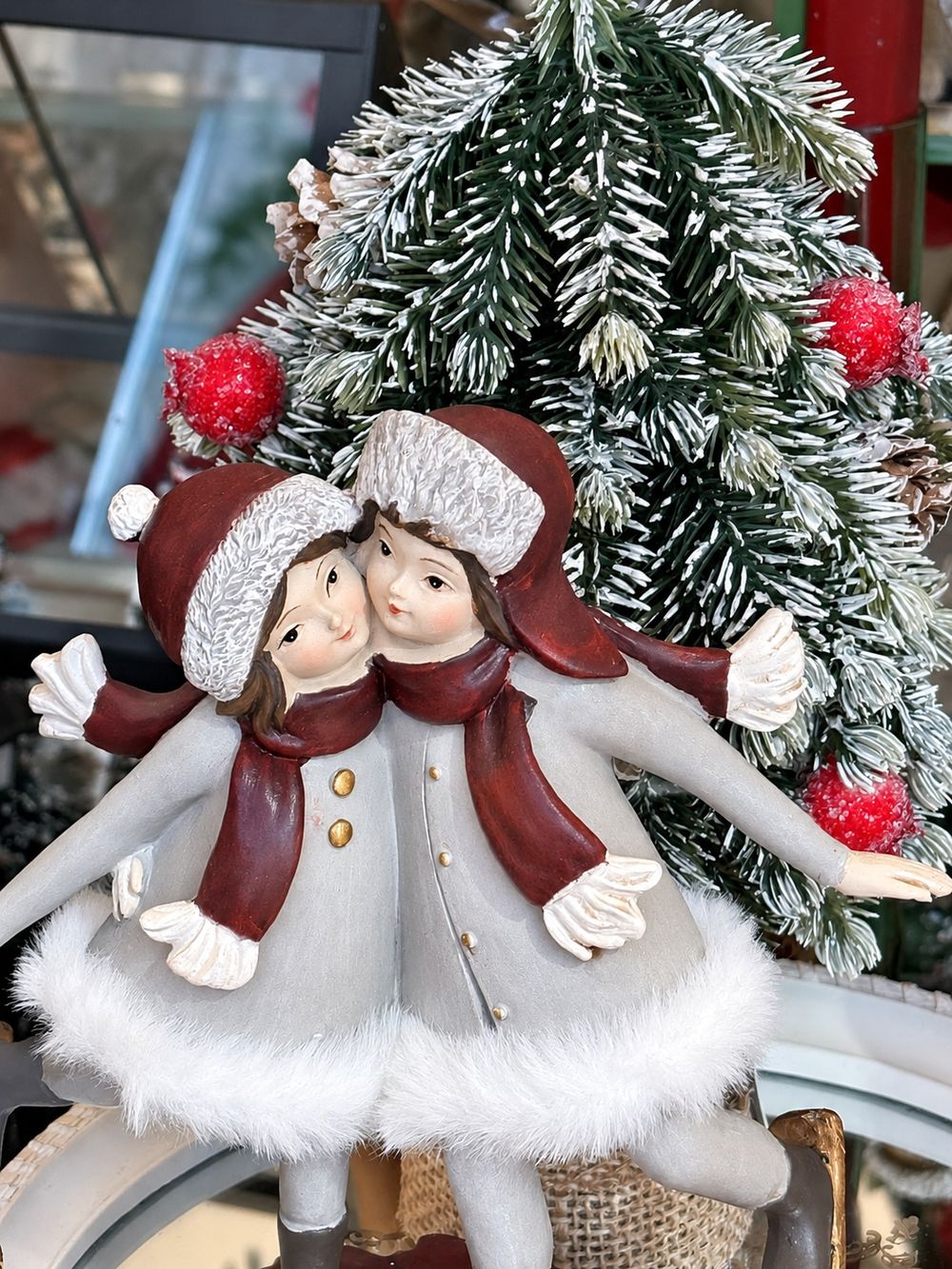 Détail des visages, bonnets blancs et écharpes bordeaux de la figurine Les Petites Skieuses.