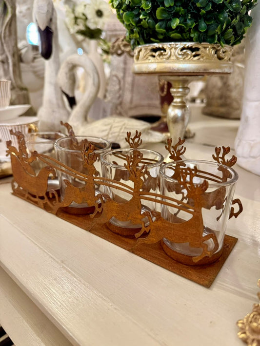 Photophore de Noël en métal rouille représentant un traîneau du Père Noël tiré par des rennes, avec 4 emplacements pour bougies chauffe-plat, style romantique et féérique
