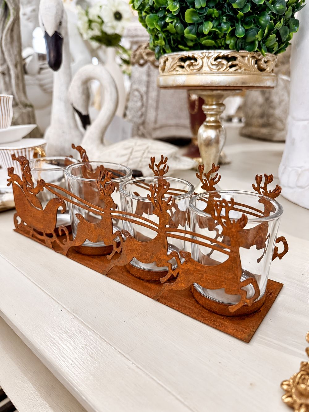 Photophore Traîneau du Père Noël en métal effet rouille et quatre verres, vu de trois quarts.