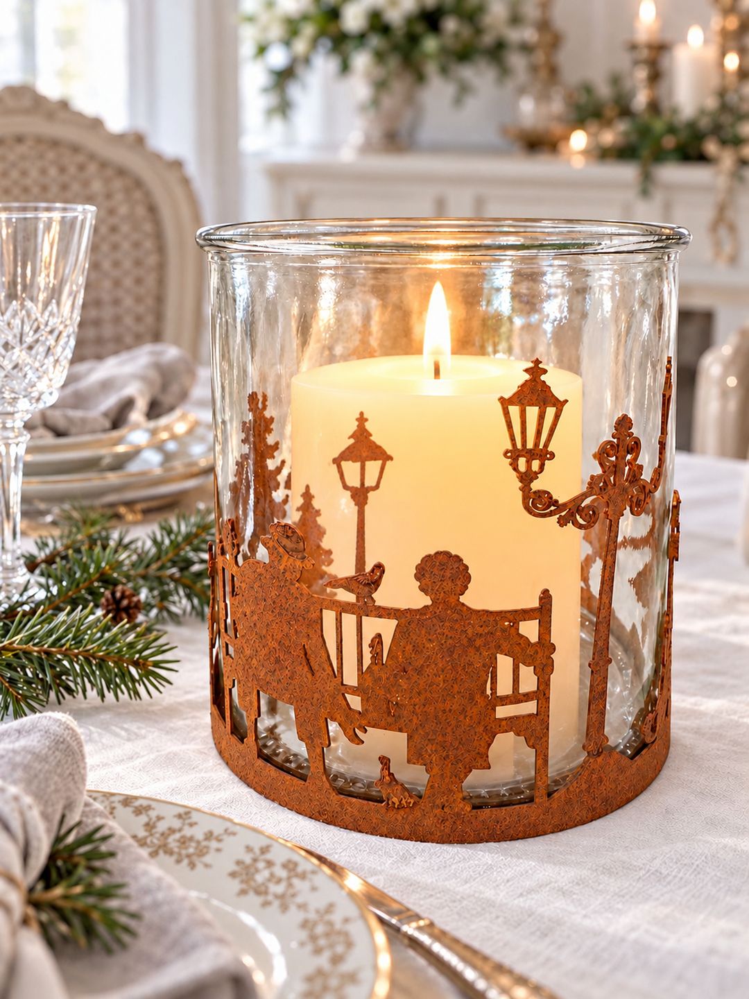 Photophore Village d’Hiver avec une grande bougie ivoire allumée sur une table de fête.