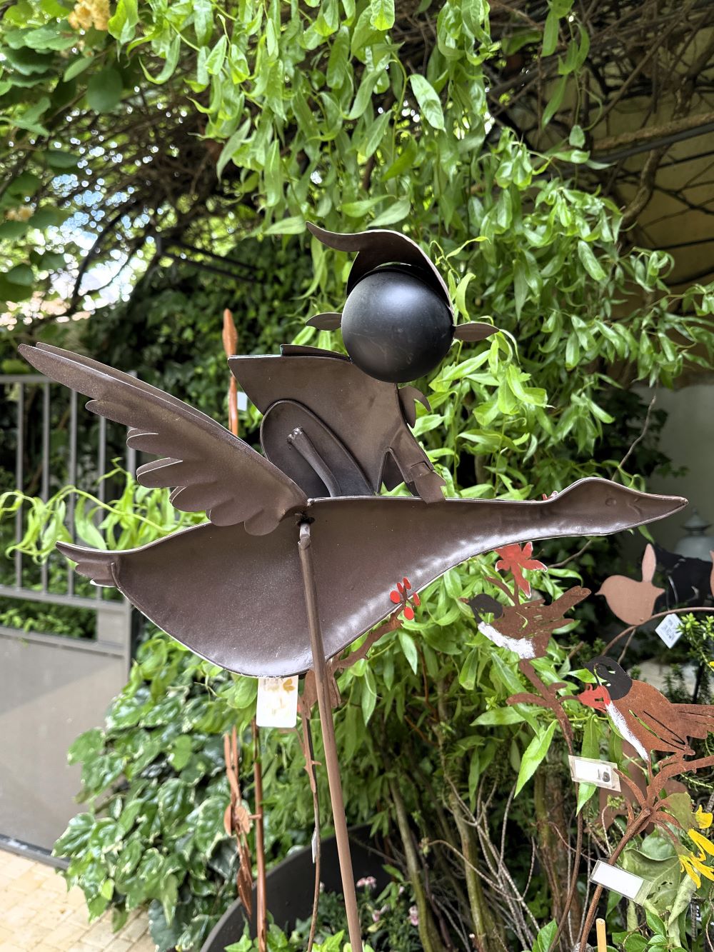 Décoration de jardin en métal représentant un lutin féérique bleu et vert sur une oie blanche en plein vol, style poétique et romantique, idéale pour un extérieur enchanteur