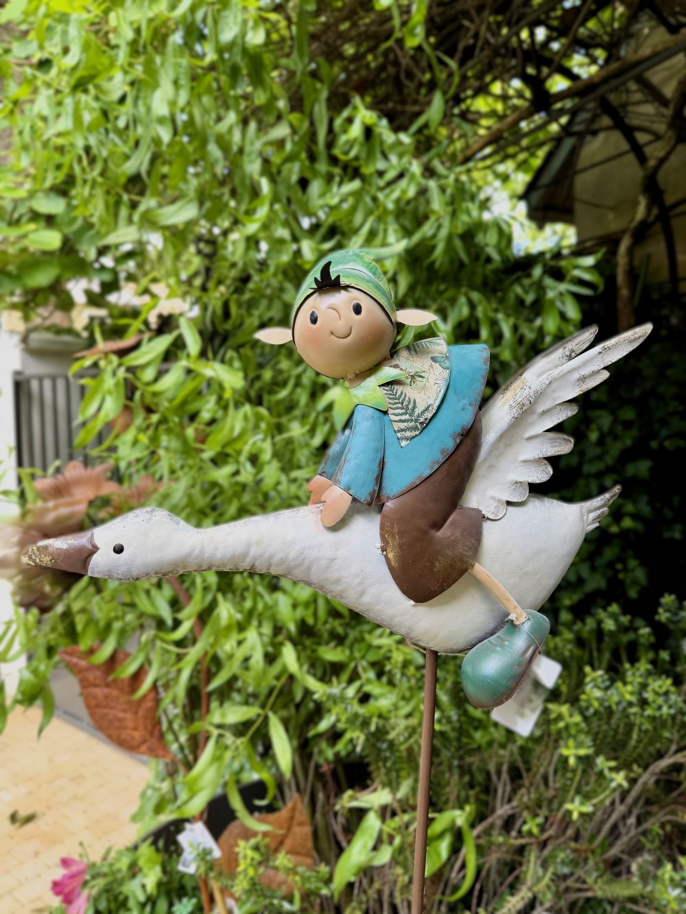 Décoration de jardin en métal représentant un lutin féérique bleu et vert sur une oie blanche en plein vol, style poétique et romantique, idéale pour un extérieur enchanteur