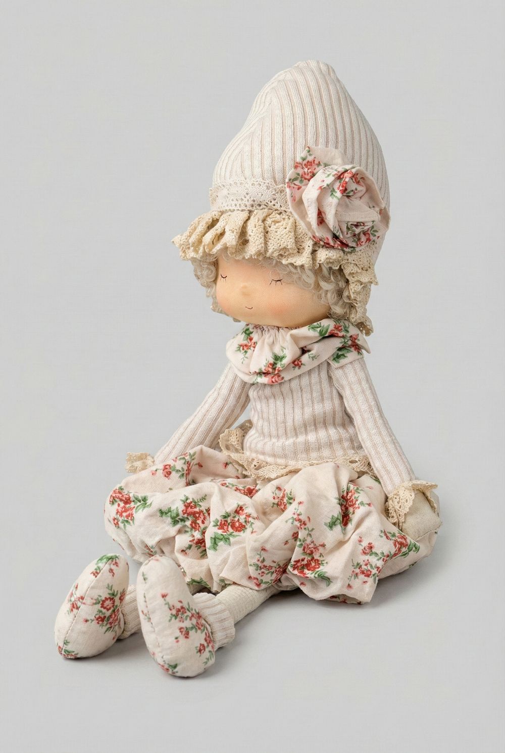 Poupée décorative bohème Liberty 45 cm en tissu beige et écru à motif floral rouge, style décoration romantique shabby chic, assise avec longues jambes souples dans une ambiance maison de charme.