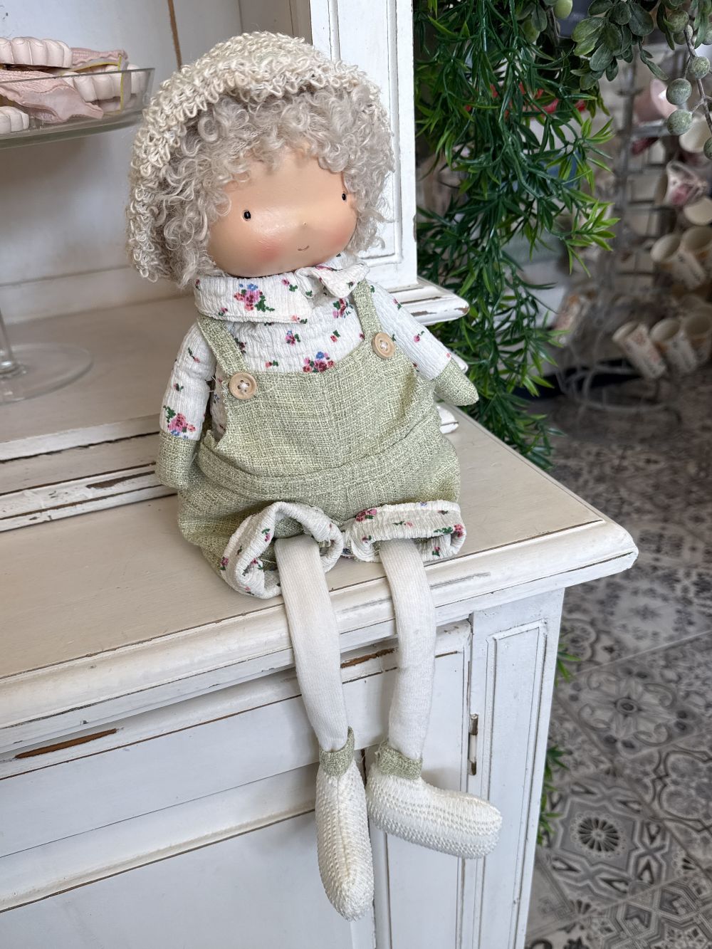 Poupée décorative assise Mr Printemps aux couleurs vert tendre, blanc et beige, style shabby chic romantique avec tenue florale et longues jambes pendantes pour décoration de charme printanière