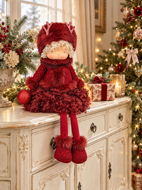 Poupée de Noël Demoiselle Bordeaux de 52 cm sur un buffet ivoire, avec sa boule rouge attachée à la main droite