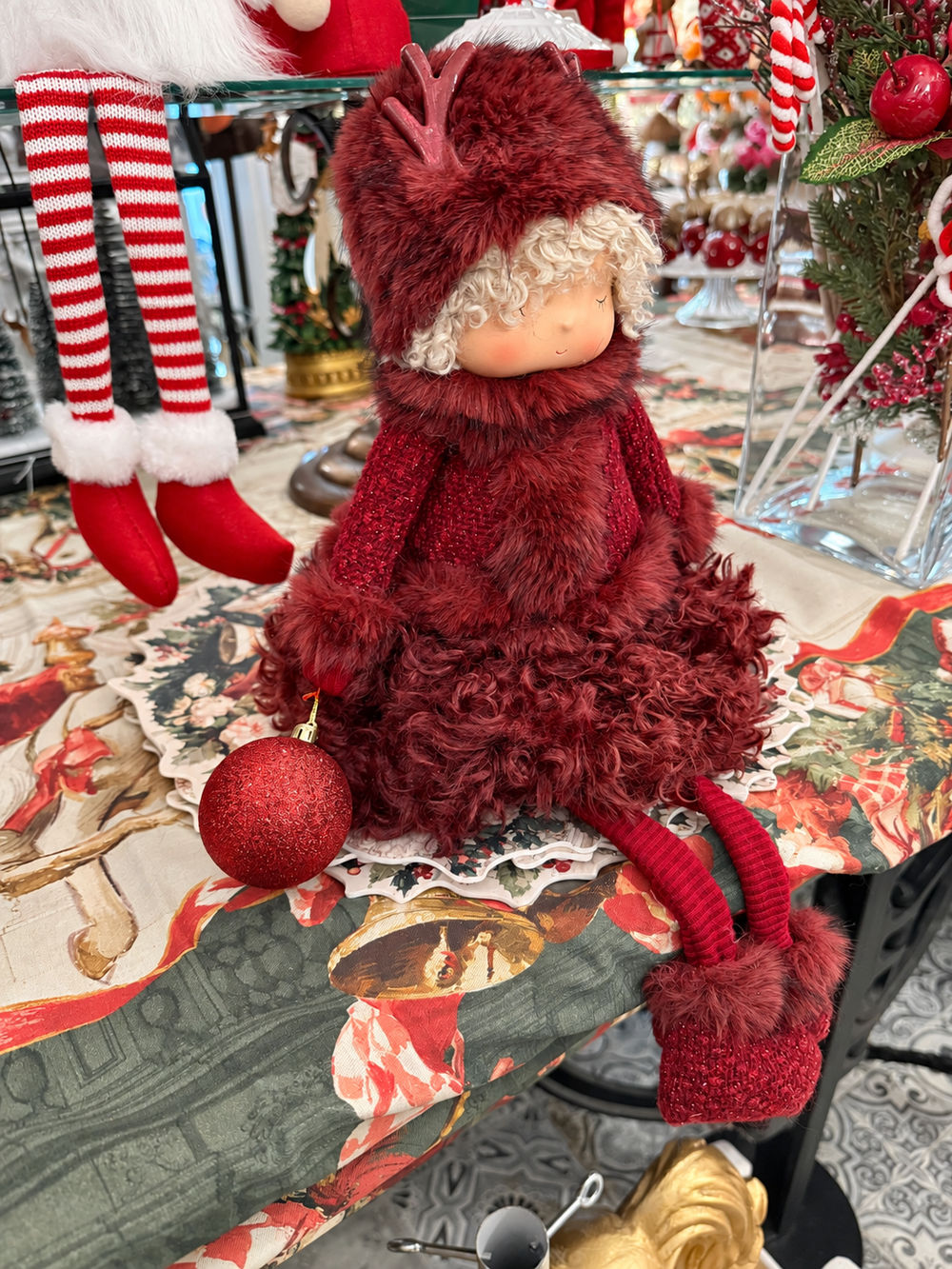 Poupée de Noël Demoiselle Bordeaux vue de trois quarts à droite, tenue bordeaux et boule rouge en main